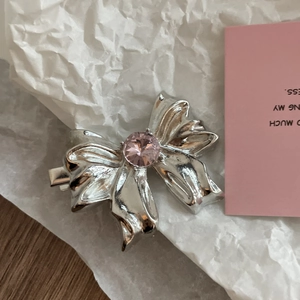Makroaufnahme der silbernen Schleifen-Haarspange mit rosa Kristall und Metalltextur