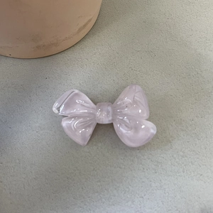 Détail d'une pince à cheveux nœud rose avec finition résine translucide et éclat nacré
