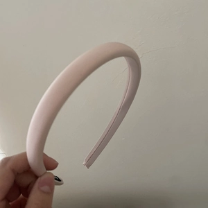 Detailed close-up of a premium satin padded headband in soft light pink fabric