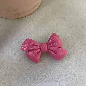 Vue détaillée d'une barrette à nœud rose brillant sur une surface en pierre grise