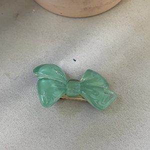 Détail d'une pince à cheveux nœud en résine marbrée verte avec base en métal doré