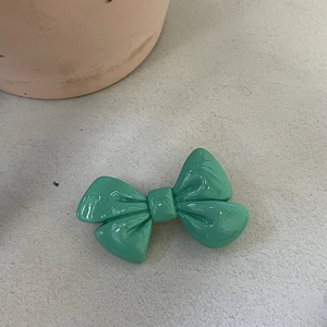 Vue détaillée d'une pince à cheveux nœud vert menthe avec un fini aspect céramique