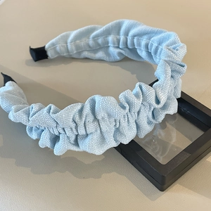 Detail of light blue pleated headband with woven texture and black protective ends