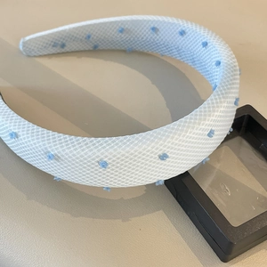Close-up of light blue padded headband with white mesh and blue plush polka dots