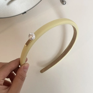 French vintage pearl headband with golden accent and soft light yellow fabric texture
