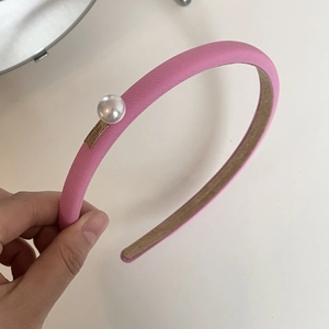 Detail of pink fabric headband with a large pearl and gold LOVEDAYS logo plate