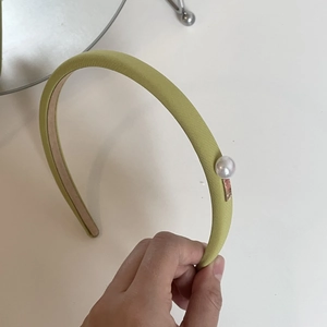 Close-up of light green fabric headband with a large pearl and golden metal buckle