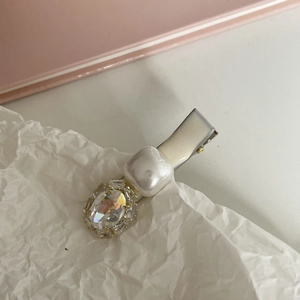 Elegant cream hair clip featuring a faceted zircon stone and pearl on white crinkle paper
