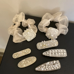 Détail des chouchous en organza blanc crème et barrettes en strass sur fond noir