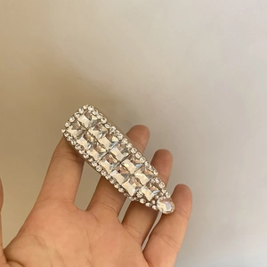Détail d'une pince à cheveux argentée avec de gros strass carrés et bordures en cristal