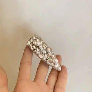 Détail d'une pince à cheveux triangulaire avec strass brillants et perles blanches