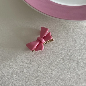 Detailopname van een roze glanzende strik haarclip op een witte getextureerde lederen ondergrond