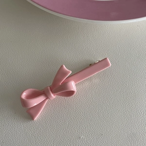Detail van roze strik haarspeld met glanzende afwerking en metalen clip