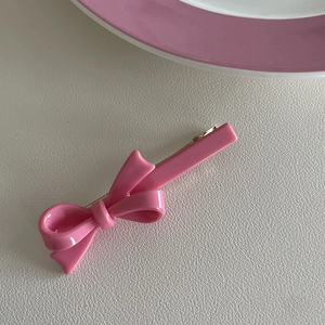 Detail van een roze strik haarclip met glanzende afwerking op lederen textuur