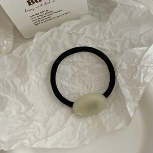 Élastique à cheveux minimaliste avec perle en acrylique vert posé sur un décor élégant