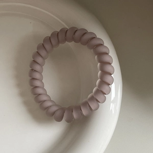 Nahaufnahme eines matten Spiralhaargummis in einer minimalistischen Keramikschale