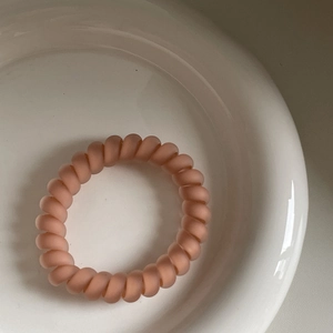 Nahaufnahme eines mattrosa Spiral-Haargummis mit hochelastischem Telefonkabel-Design