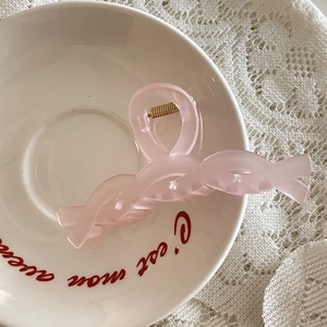 Pince à cheveux torsadée rose mat élégante pour femme sur fond de dentelle romantique