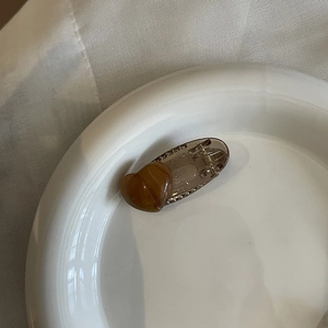 Translucent brown heart hair claw clip with rhinestones on white ceramic tray