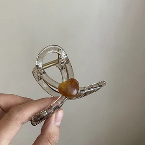 Handheld amber translucent hair claw clip with a marble heart design for women