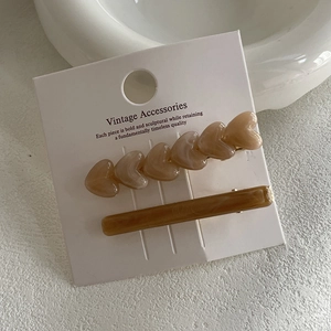 Two-piece marble pattern heart hair clip set on display card in cream and brown