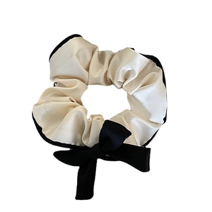 Elegant ivory satin hair scrunchie with black trim and ribbon bow for low ponytail styles