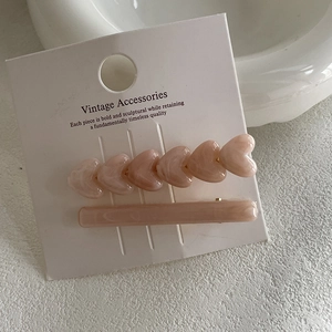 Close-up of pink heart hair clip set with marble texture on display card