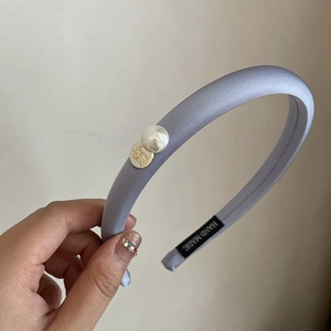 Detail view of light purple satin sponge headband with pearl and gold pendant charm