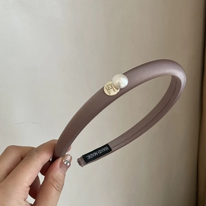 Close-up of padded satin headband with elegant pearl decoration and gold pendant detail