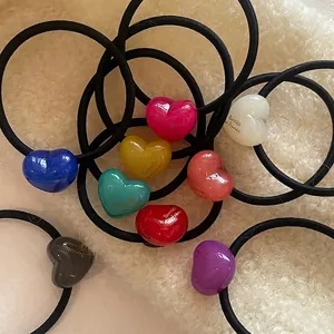 Colorful acrylic heart hair ties with Barrette France text on plush cream background