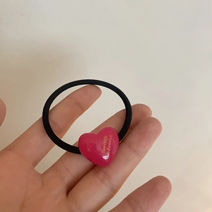 Detail of pink resin heart hair tie with France text on high elastic black band