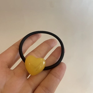 Detailed close-up of a yellow acrylic heart-shaped hair tie with Eunice letter engraving