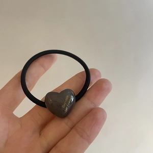 Detail of heart hair tie featuring brown resin heart with gold Barrette engraving