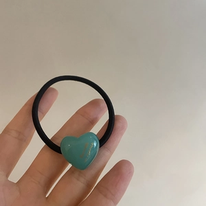 Close-up of heart-shaped hair tie with golden Bonjour engraving and elastic band