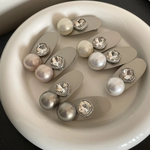 Eleganti fermagli per capelli in argento con grandi perle e strass su piatto ceramica