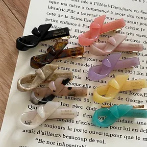 Elegant French handmade acetate bow hair clips in multiple colors on a book background