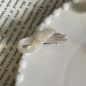 Detailed macro of cream acetate bow hair clip with gold metal spring on vintage book