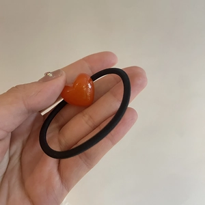 Close-up of heart-shaped acrylic charm on a high-elastic black hair tie for girls