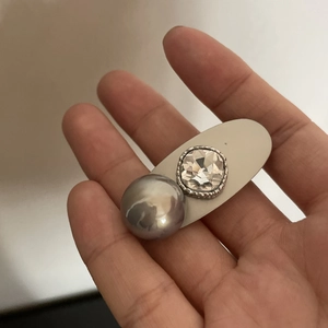 Dettaglio molletta per capelli con base beige opaca, perla grigia e cristallo sfaccettato