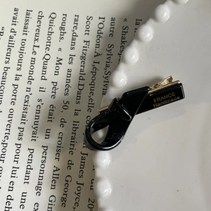 Close-up of black acetate bow hair clip with gold France Handmade logo on a white plate