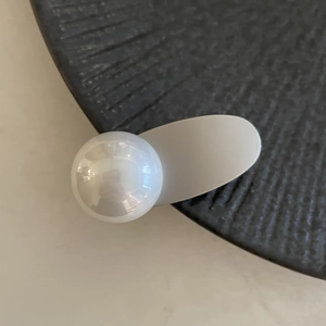Macro di un fermaglio per capelli minimalista con grande perla bianca su base opaca