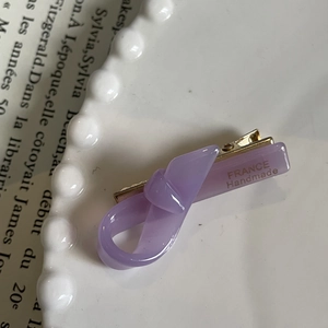 Elegant purple handmade hair clip with gold France label on a vintage tray display