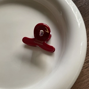 Detail of red acetate hair claw with heart cutout, rhinestone and France Handmade logo