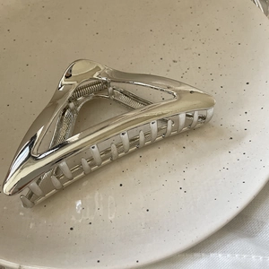 Detailed view of large silver geometric triangular metal hair claw with high-gloss finish