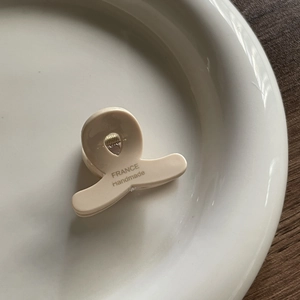 Detail of cream acetate mini hair claw clip featuring France Handmade text on ceramic tray
