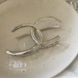Macro detail of the polished silver metal hair claw clip with interlocking C design