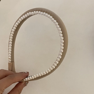 Gros plan sur un élégant serre-tête double couche en perles et tissu beige raffiné