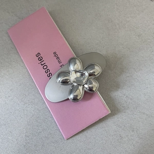 Silver metal hair clip with crystal flower detail on a pink display card for women
