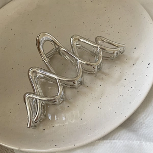 Detailed macro view of the silver metallic hair claw clip with its wavy geometric design