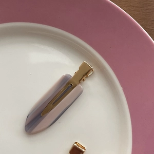 Detailed macro view of pink marbled acetate hair clip with golden metal alligator base